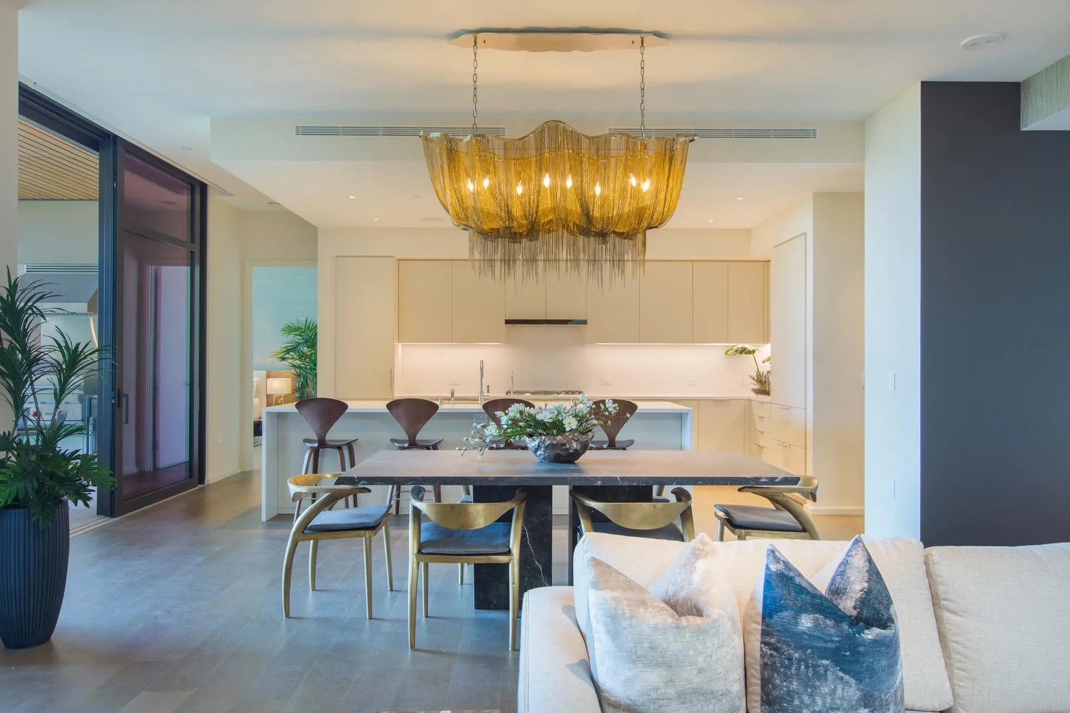 A modern open-plan living and dining area with a table beneath a large pendant light.