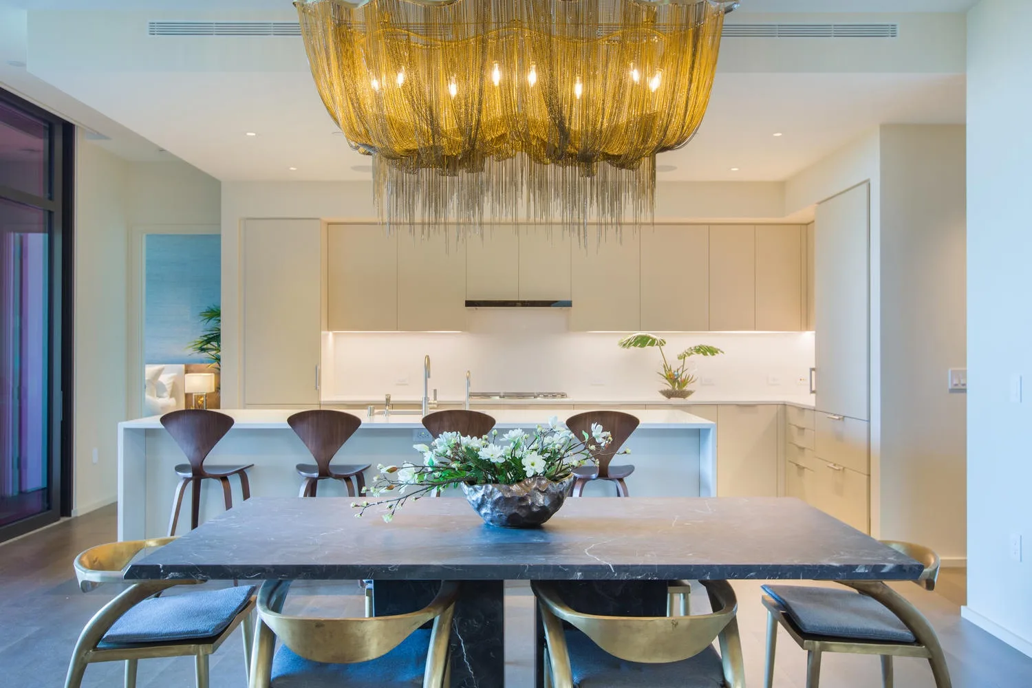 A dining area with a long table beneath a large pendant light.