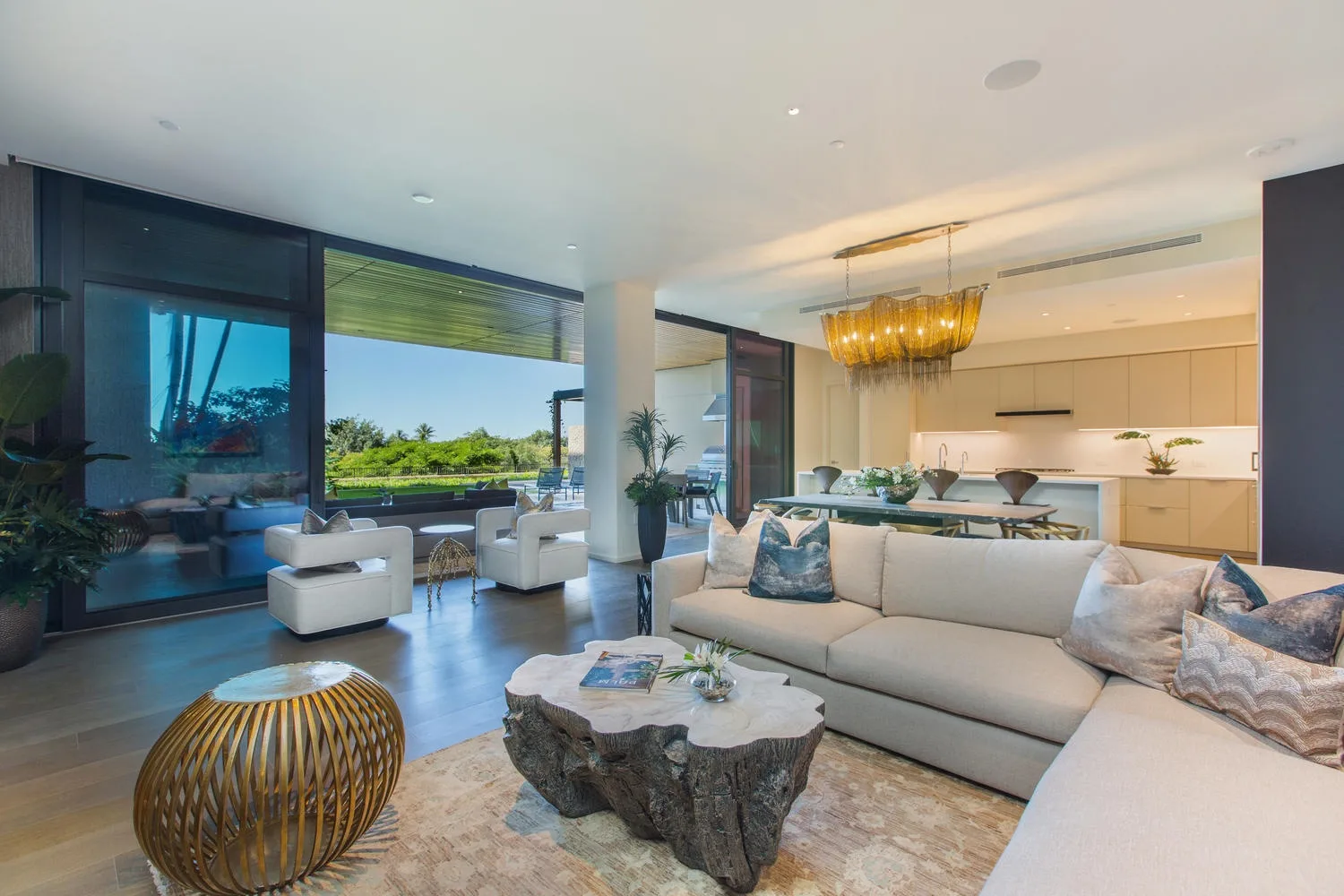 A bright open-plan living room and kitchen with large windows and a dining table.
