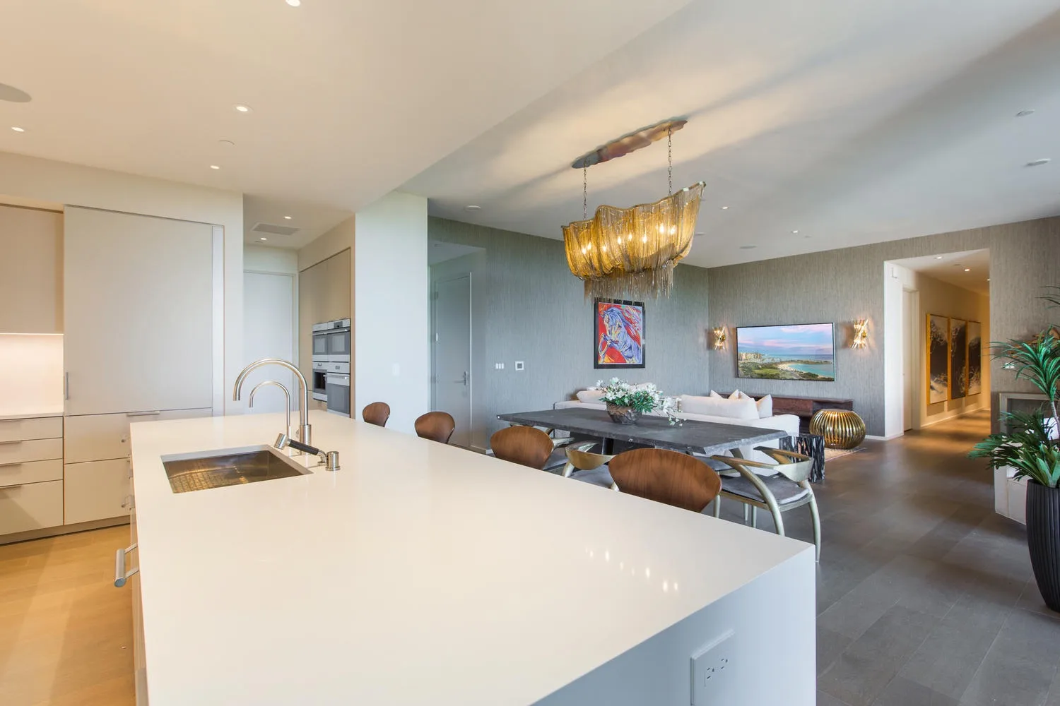 An open kitchen and dining area with a large white island and pendant lighting.