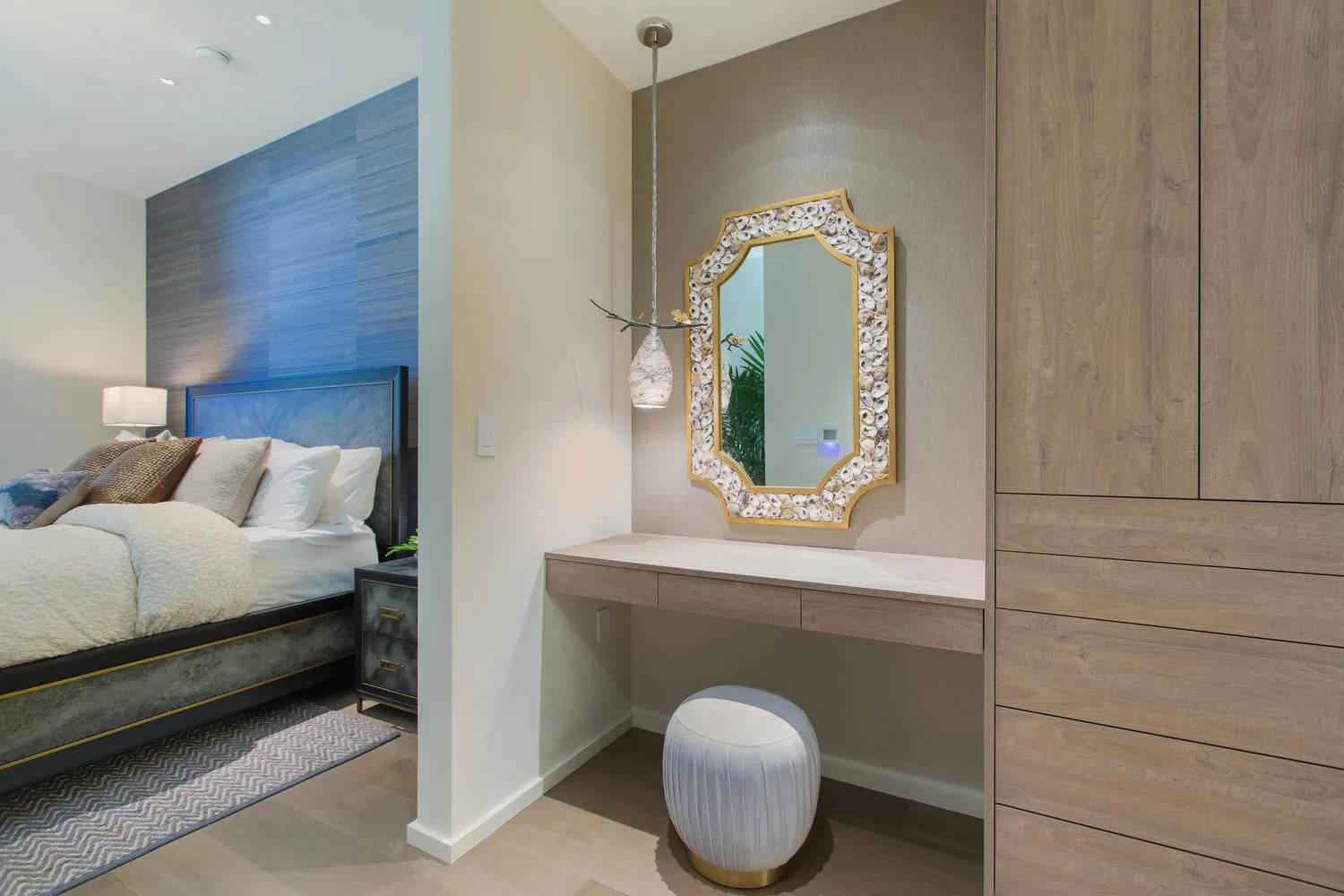 A bedroom with a bed beside a vanity and decorative mirror.
