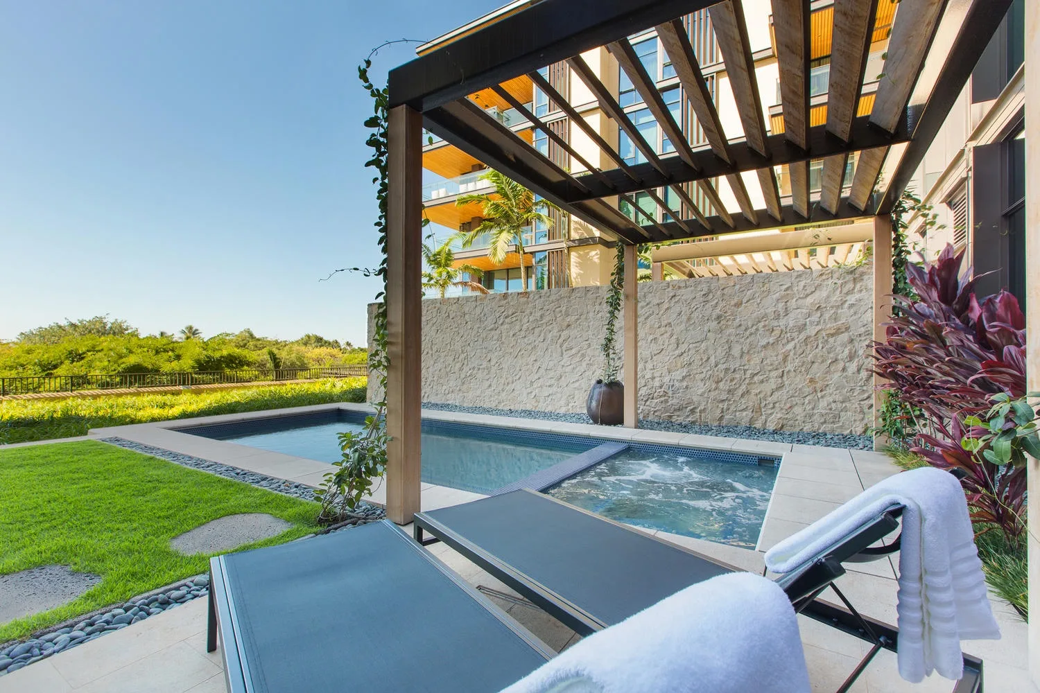 Outdoor patio with a small pool, lounge seating, and a slatted pergola.
