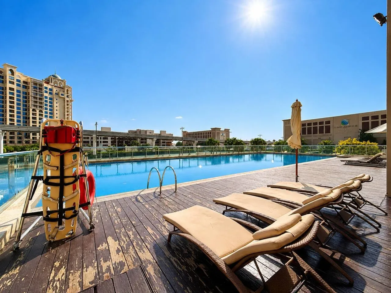 Una piscina al aire libre está junto a una terraza de madera con asientos reclinables.