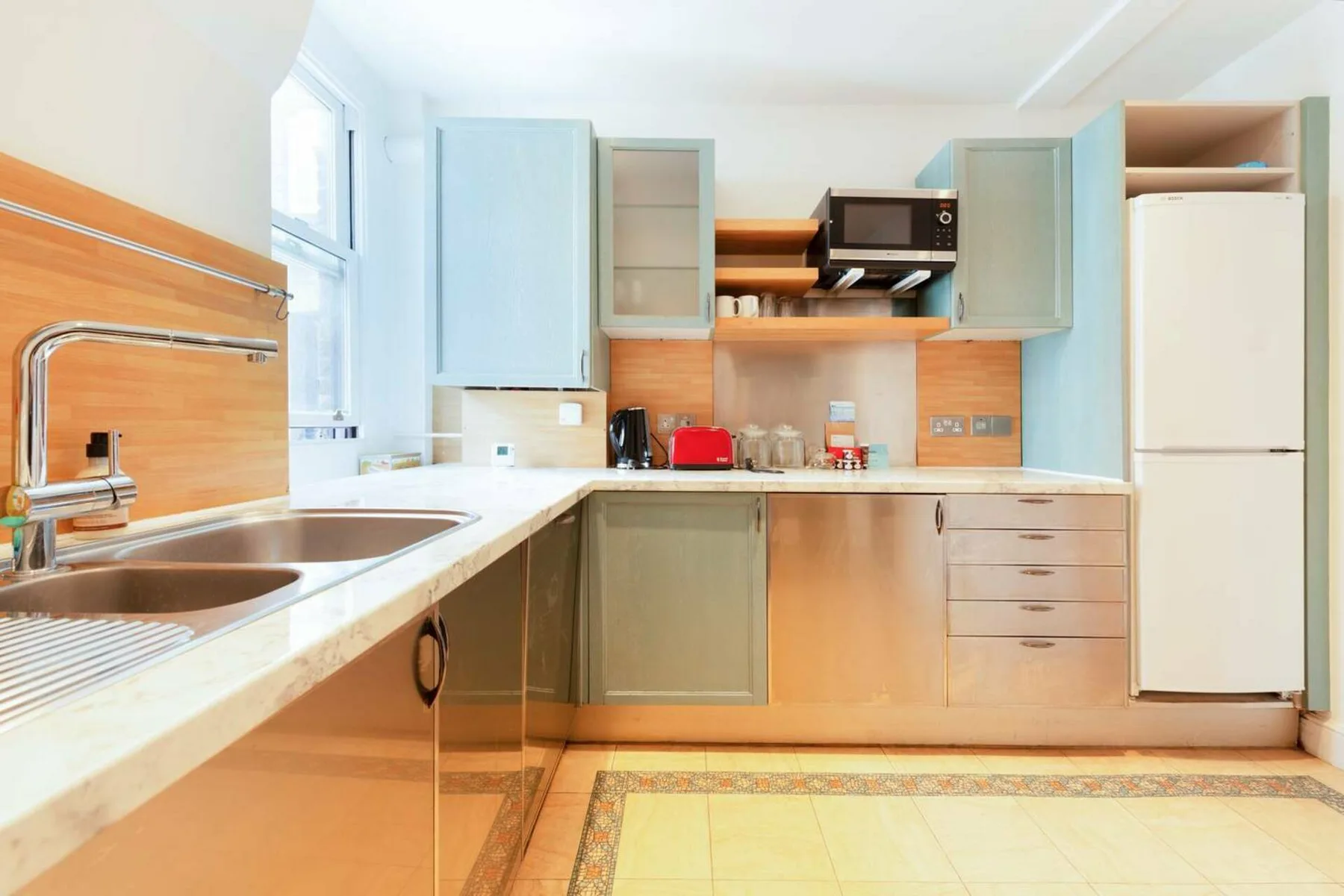 Una cocina luminosa con gabinetes claros y una encimera larga.