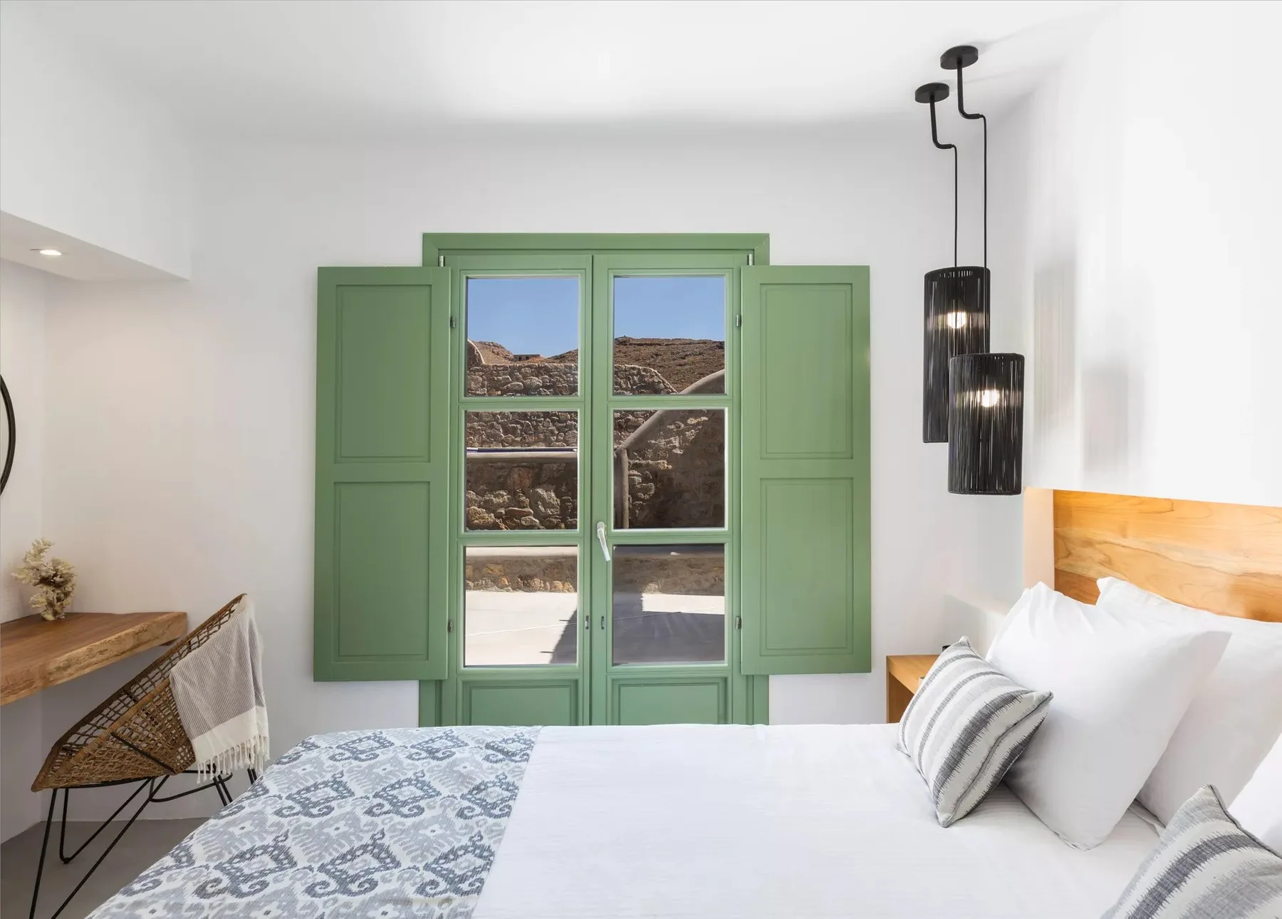 A bright bedroom with a bed beside green-framed windows.