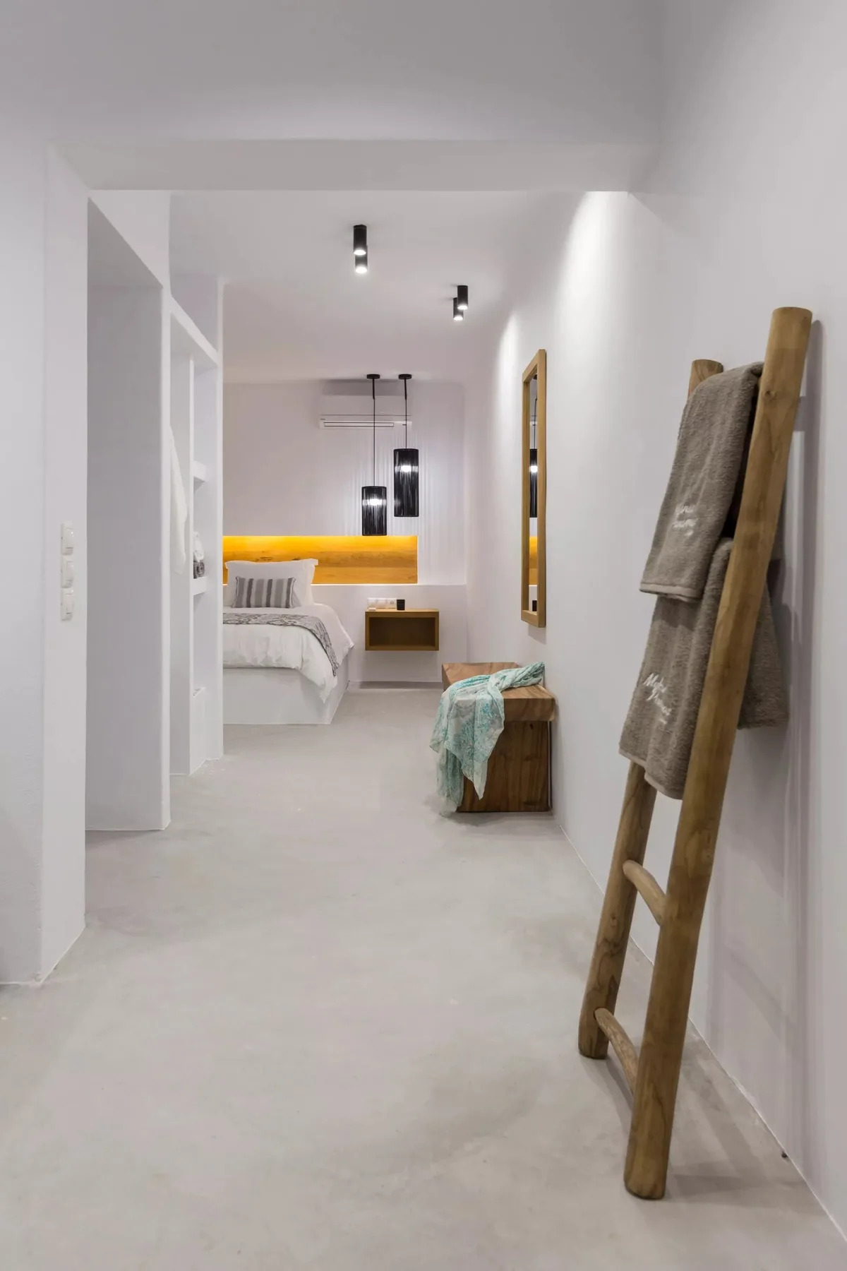 A bright bedroom with a bed and a wooden ladder leaning against the wall.