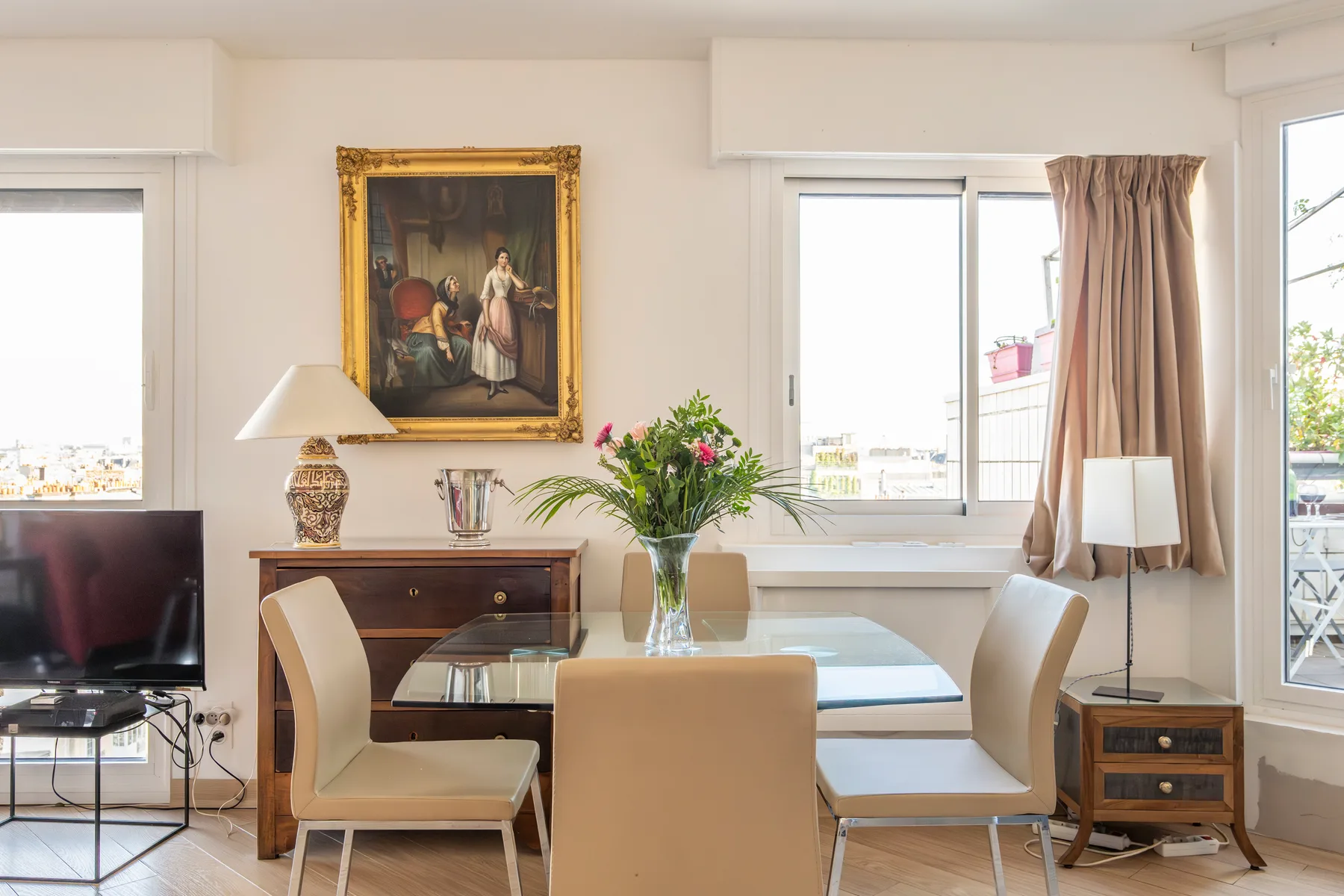 A bright living room with a dining table, seating, and large windows.