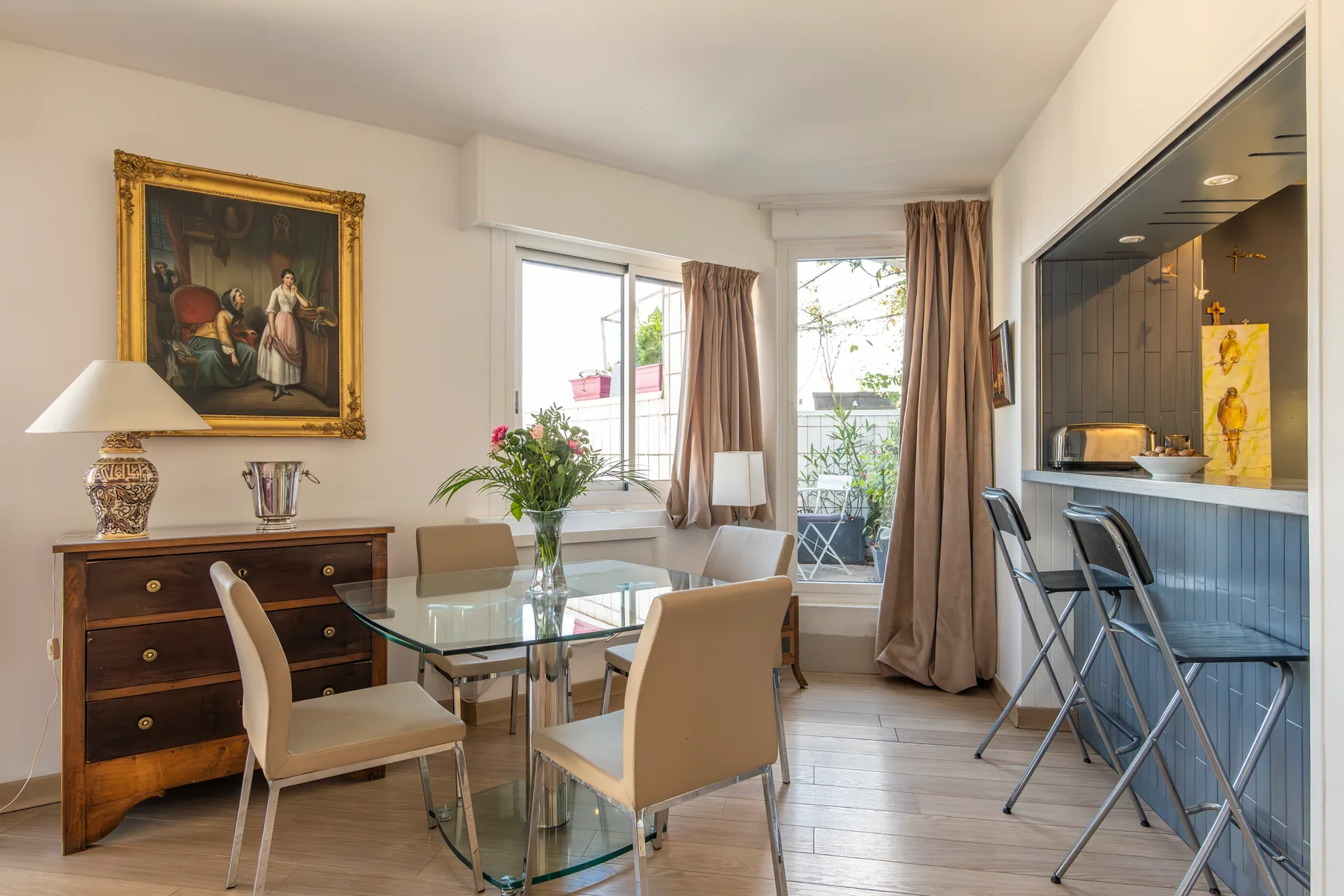 A bright dining area with a glass table beside a kitchen counter.