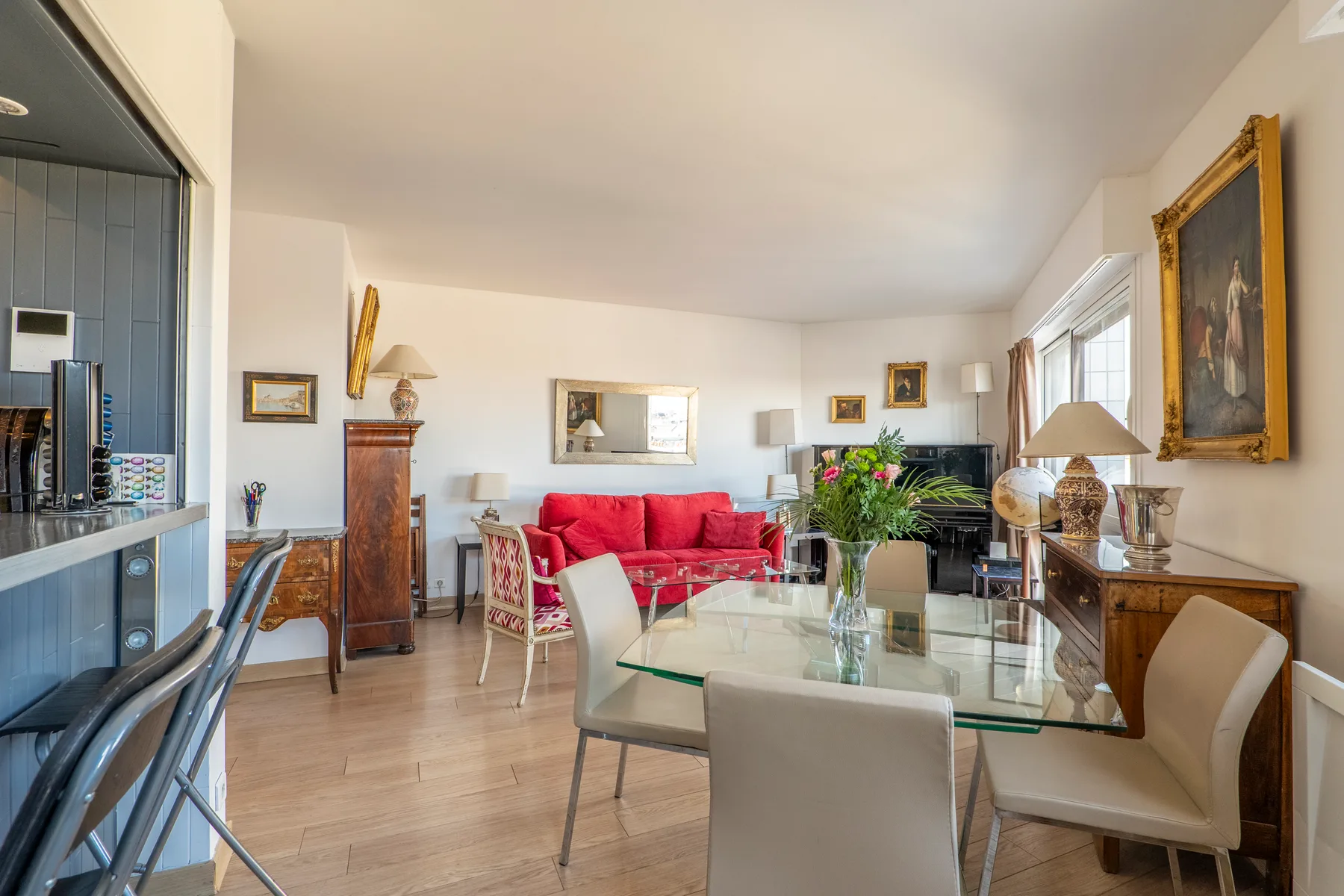 A bright living and dining area with red seating, a glass table, and large windows.