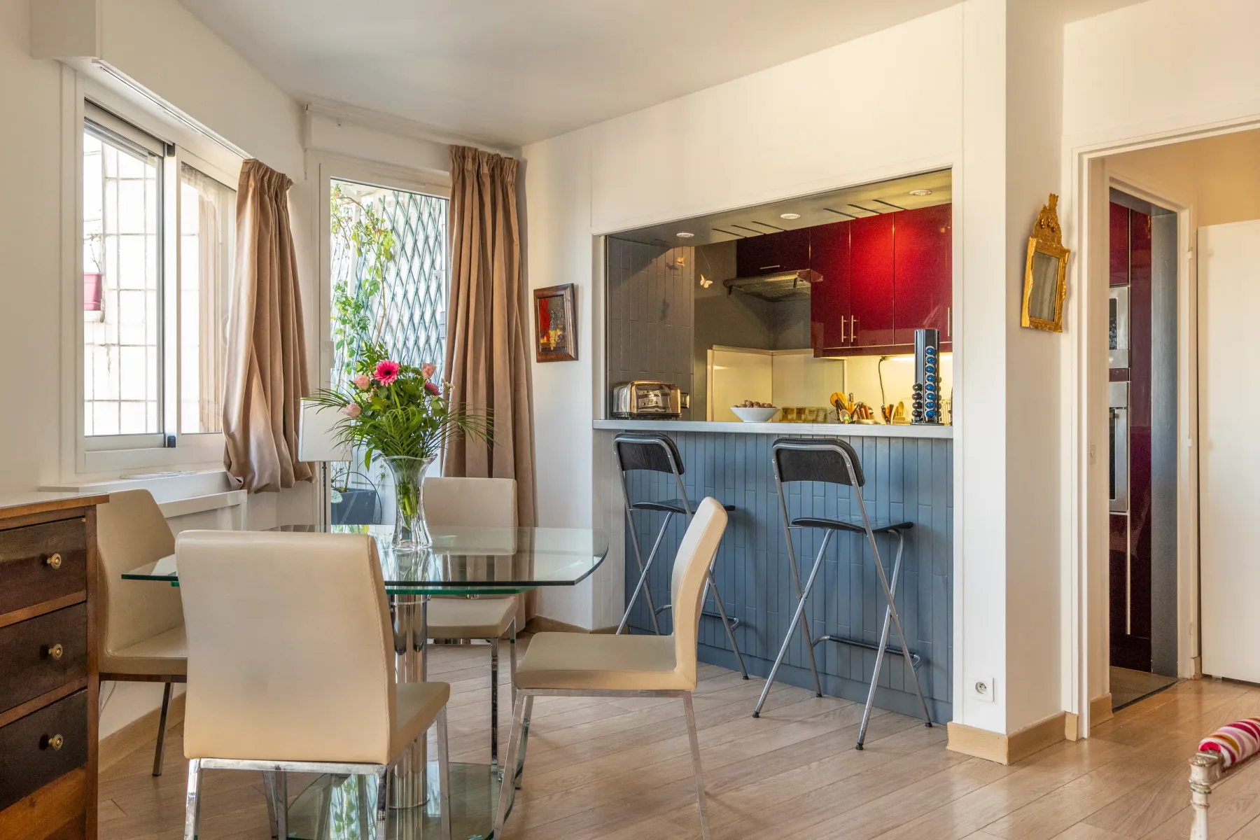 A dining area with a glass table and an open kitchen counter.