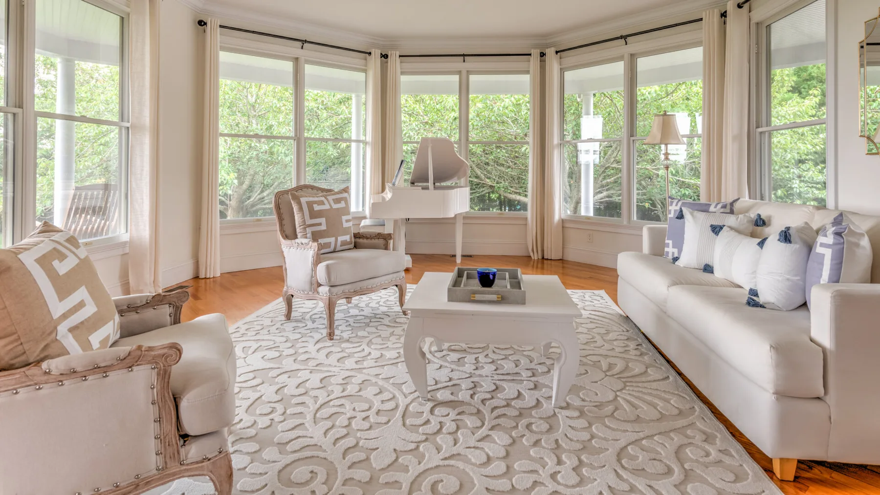 Una sala luminosa con asientos alrededor de una mesa baja, rodeada de grandes ventanas.