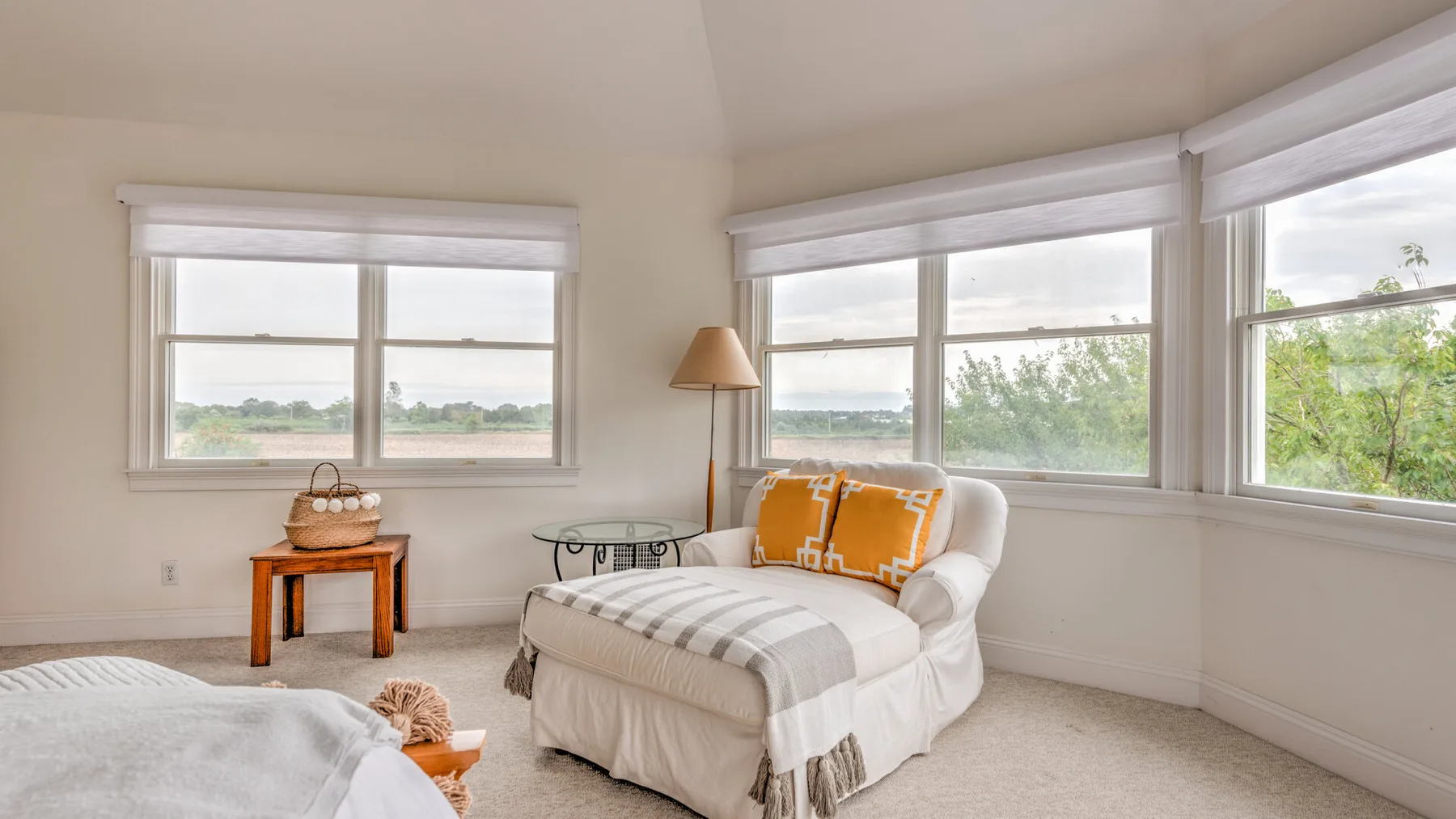 Una luminosa sala de estar con un sofá blanco junto a varias ventanas grandes.