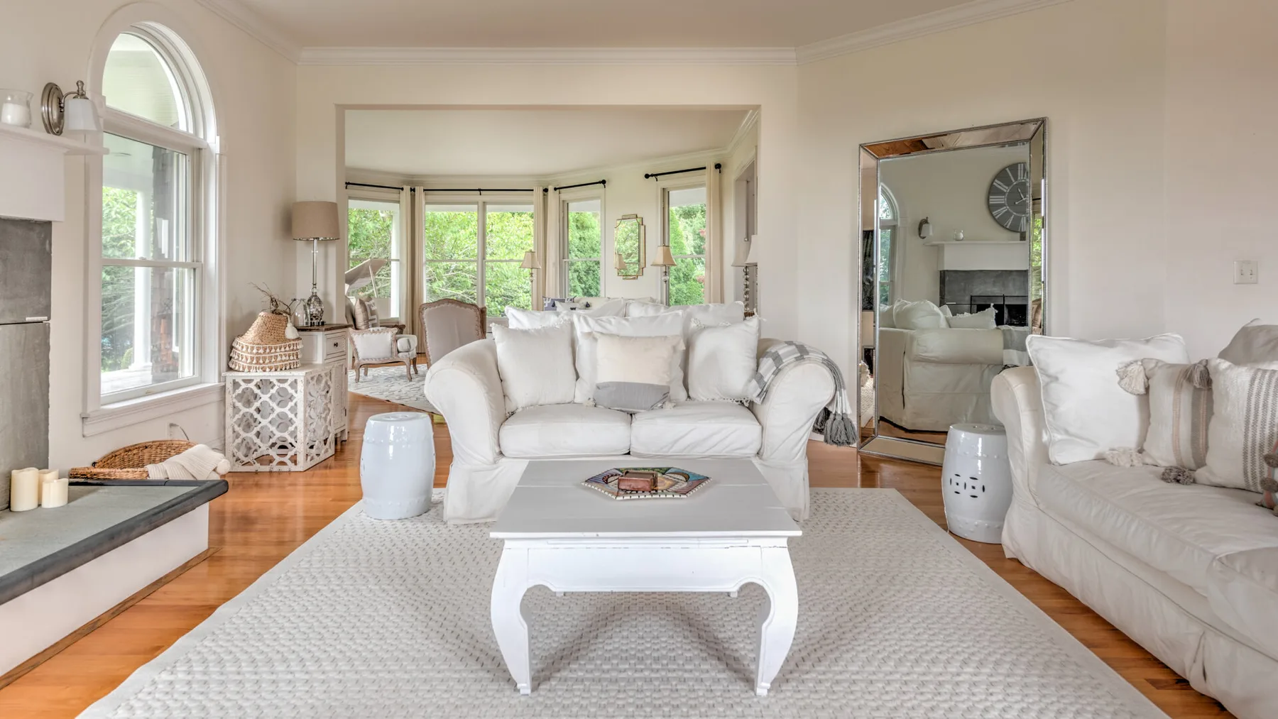Una sala luminosa con asientos blancos, una mesa de centro y grandes ventanas.