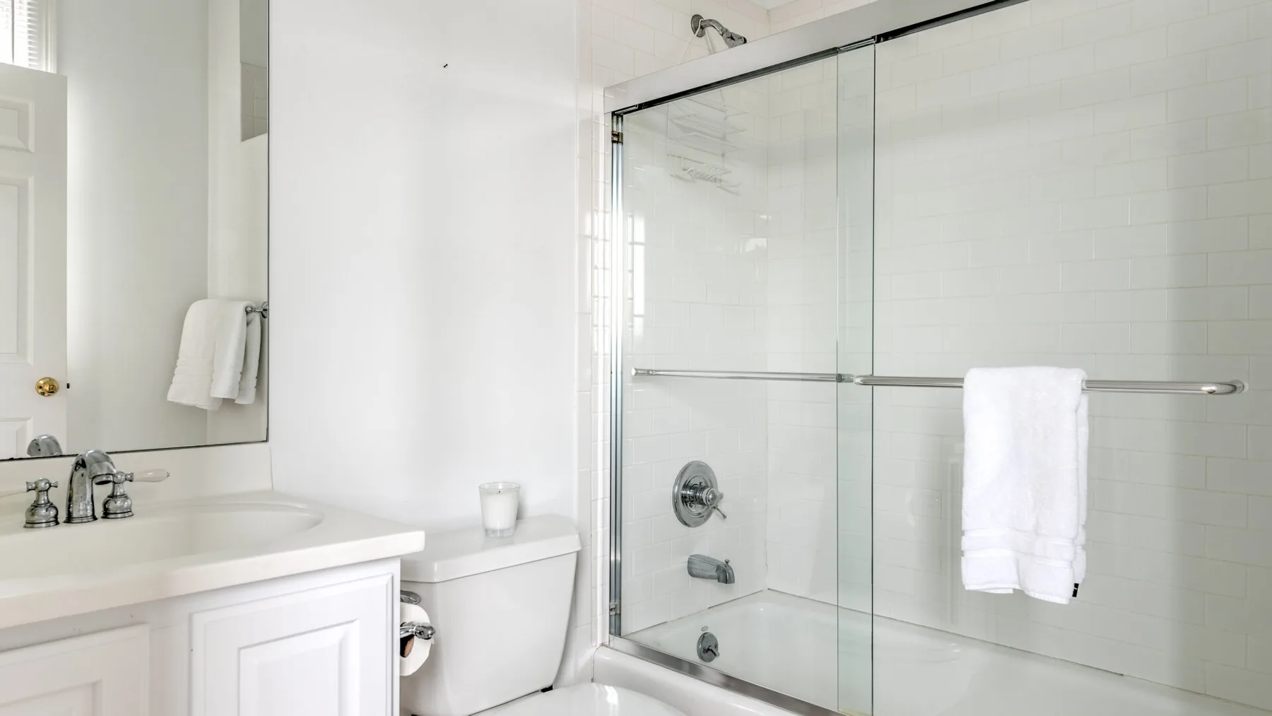 Un baño luminoso con ducha de vidrio y tocador blanco.