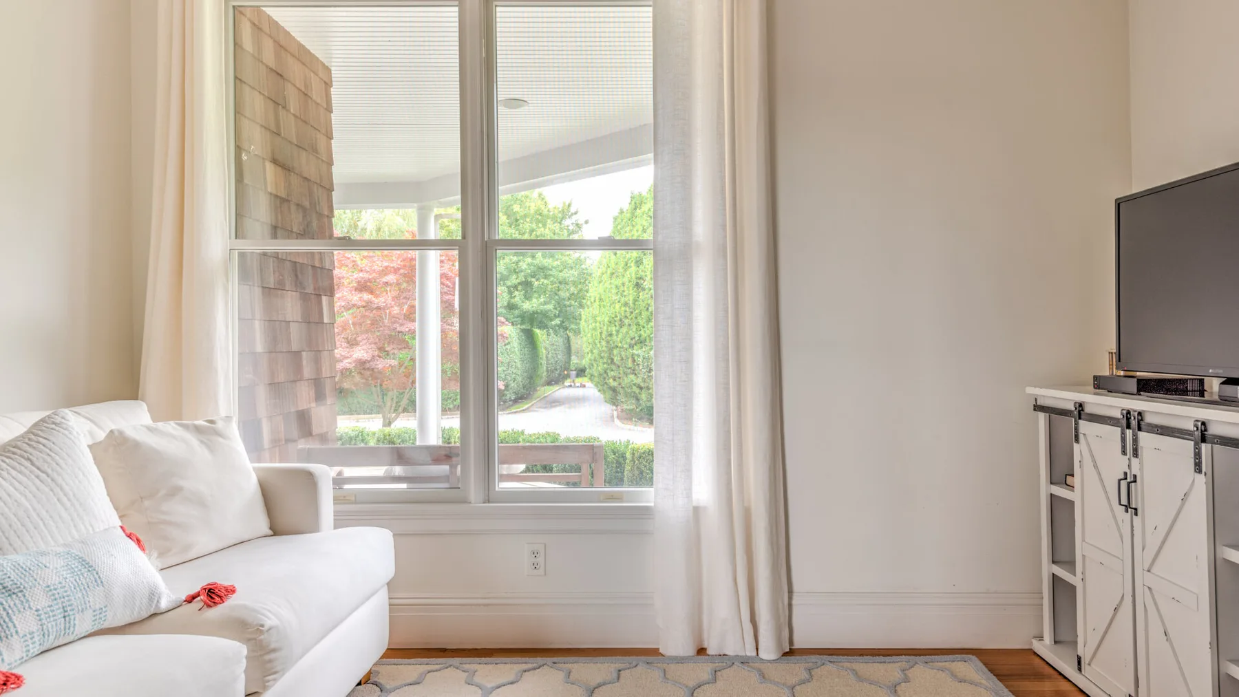 Una sala luminosa con asientos junto a una ventana grande con vistas a la vegetación.