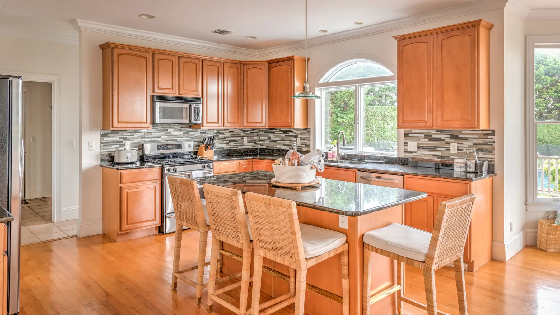 Una cocina luminosa con gabinetes de madera, una isla central y varios asientos.