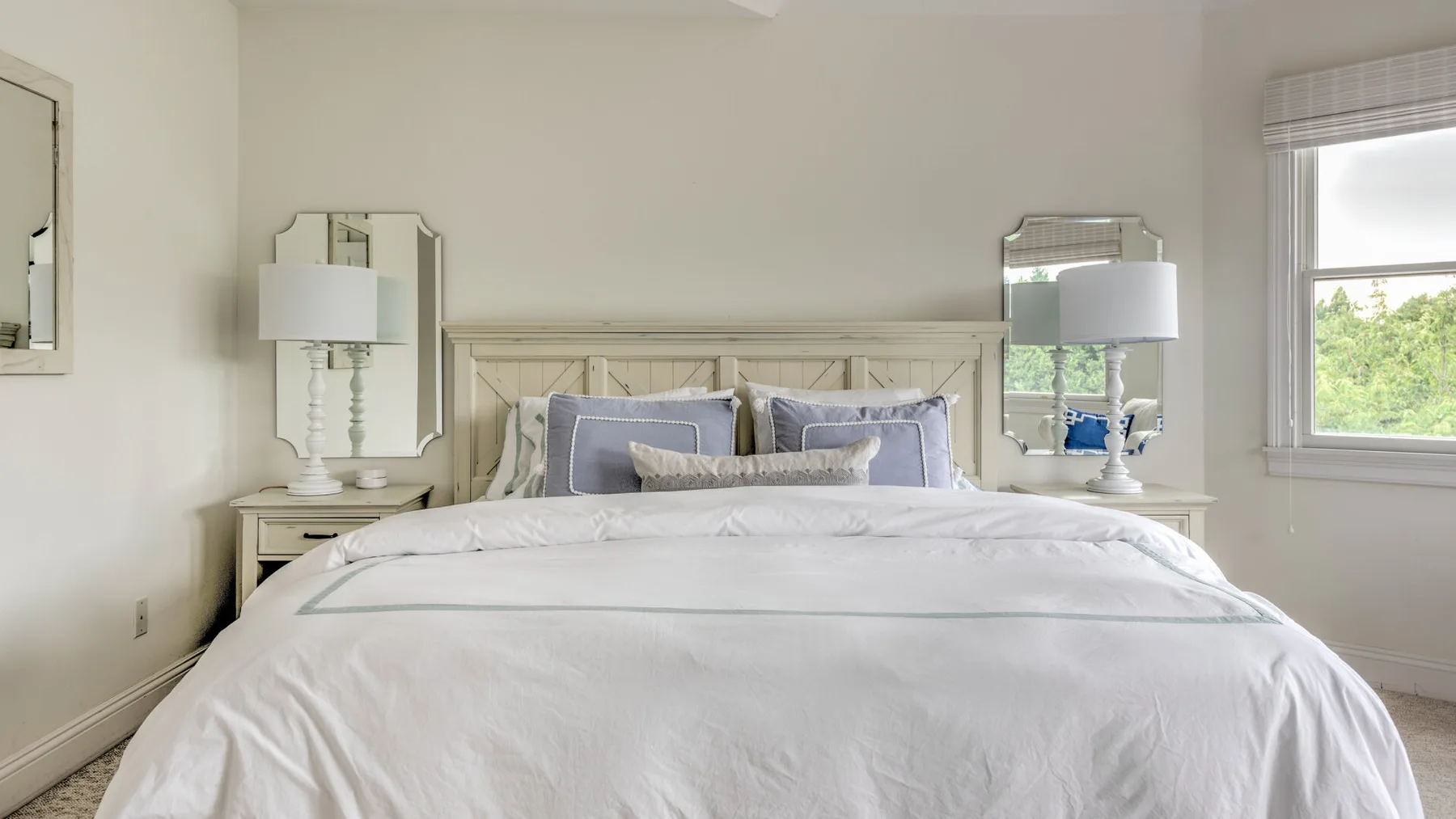 Un dormitorio con una cama bien tendida y lámparas a ambos lados.