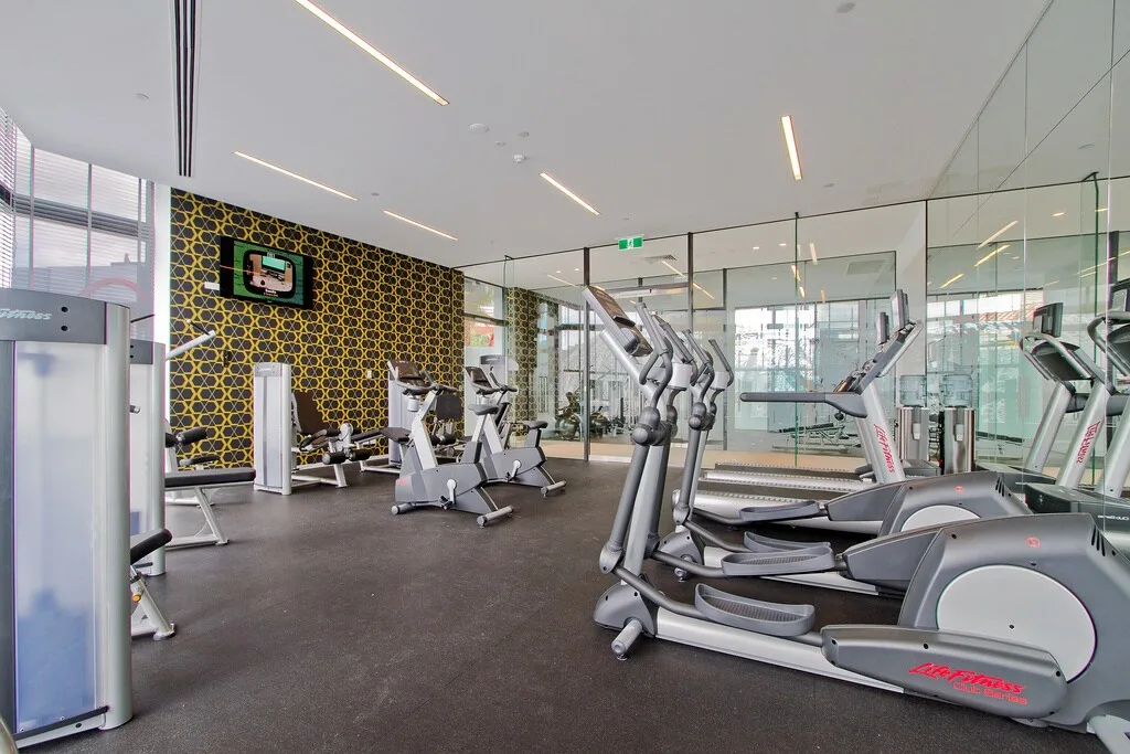 Un gimnasio con máquinas de ejercicio y paredes con espejos.