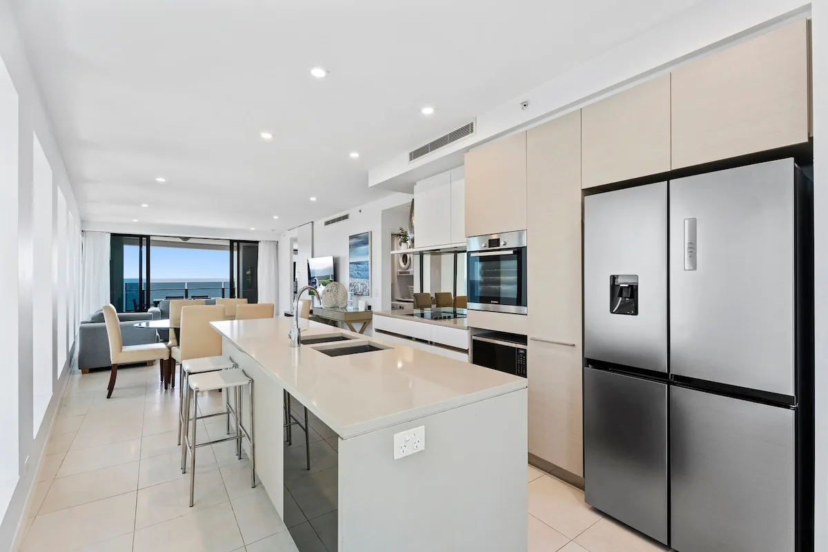 Una cocina moderna con una isla grande y vistas al océano por las ventanas.