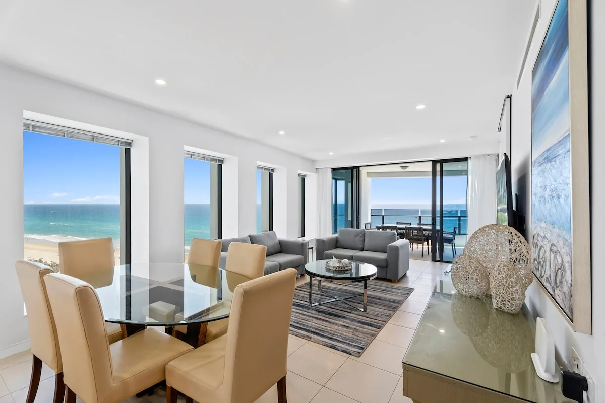 Sala de estar y comedor con asientos y grandes ventanas con vistas al océano.