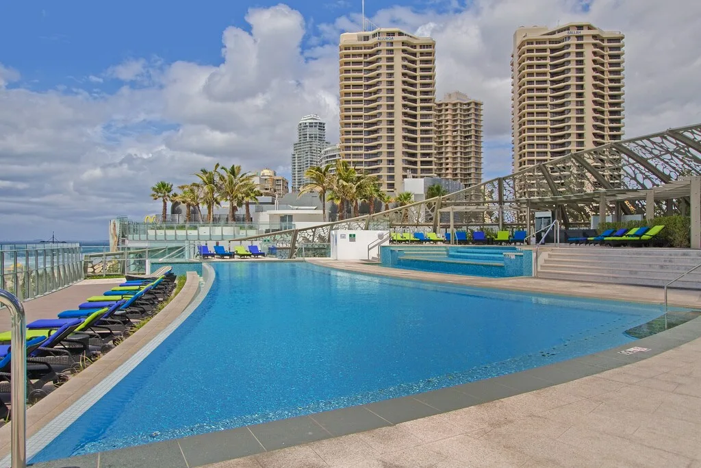 Una piscina al aire libre está junto a asientos y edificios altos.