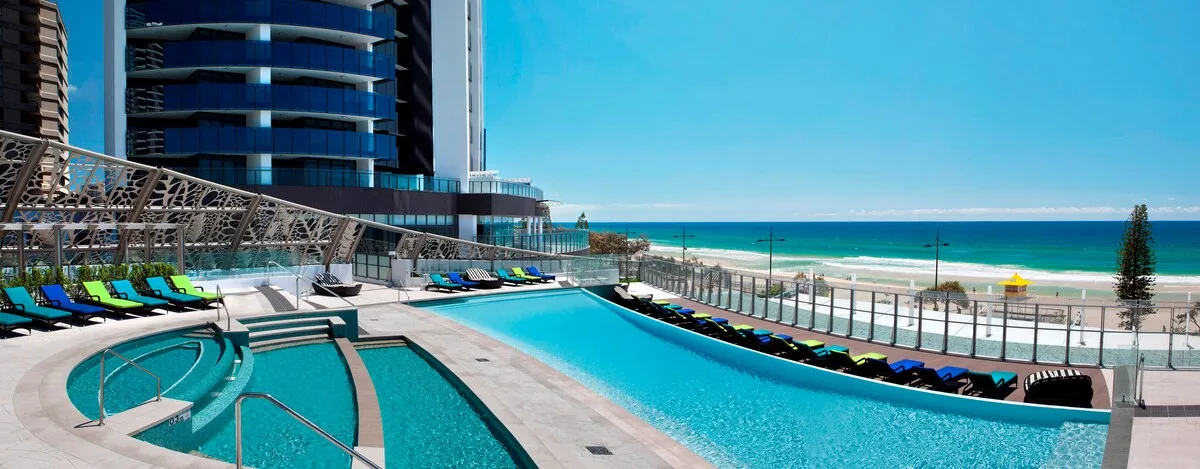 Una piscina en la azotea da a la playa y al océano junto a un edificio moderno.