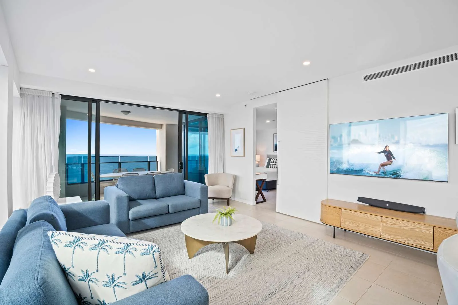 Sala de estar con asientos azules y una gran ventana con vistas al océano.