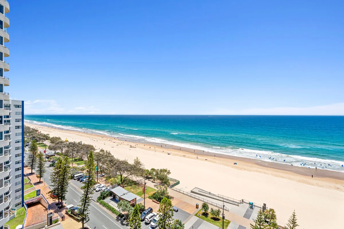 Una amplia playa de arena bordea el océano junto a un paseo marítimo.