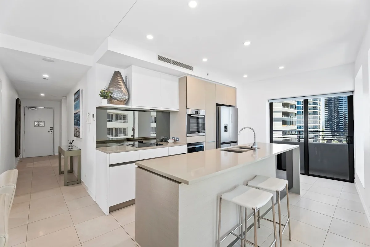 Una cocina moderna y luminosa con una isla central y ventanas amplias.