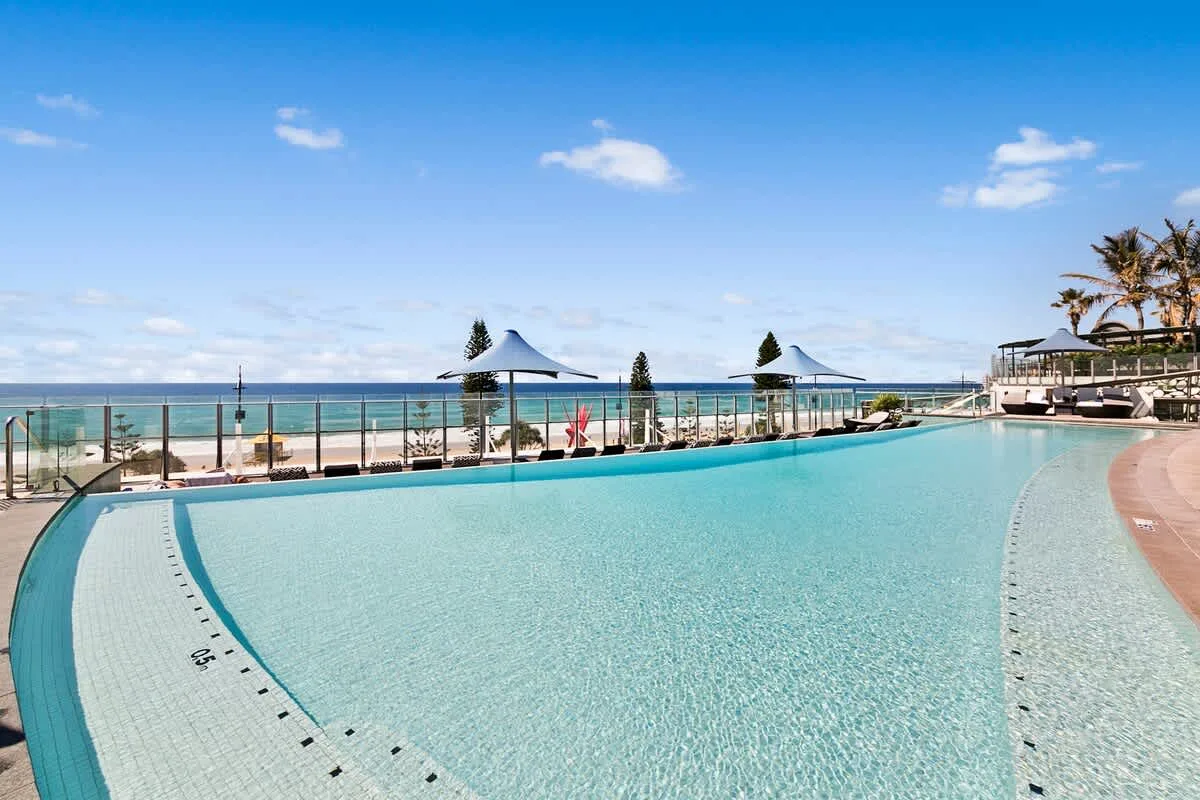 Una piscina al aire libre ofrece vistas al océano bajo un cielo azul despejado.
