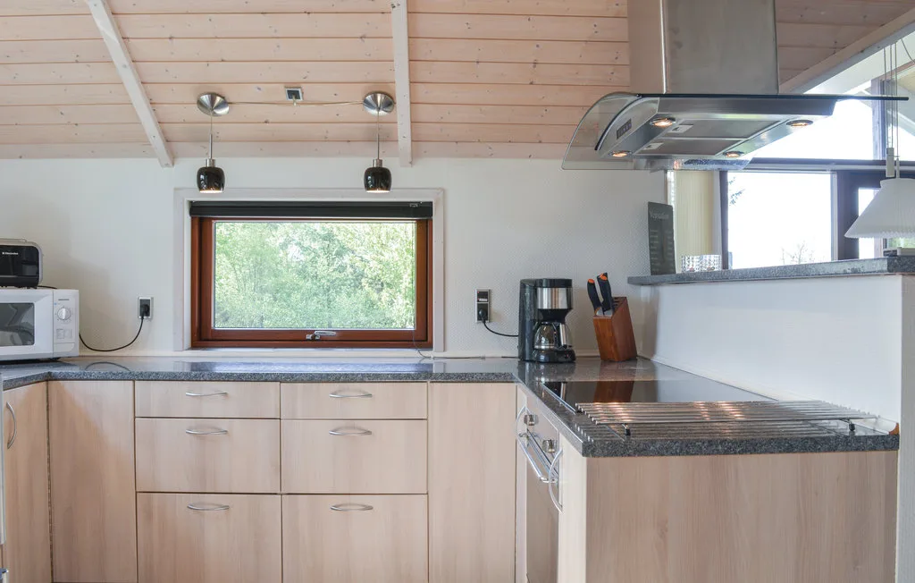 Una cocina con armarios de madera clara, una encimera y una ventana.