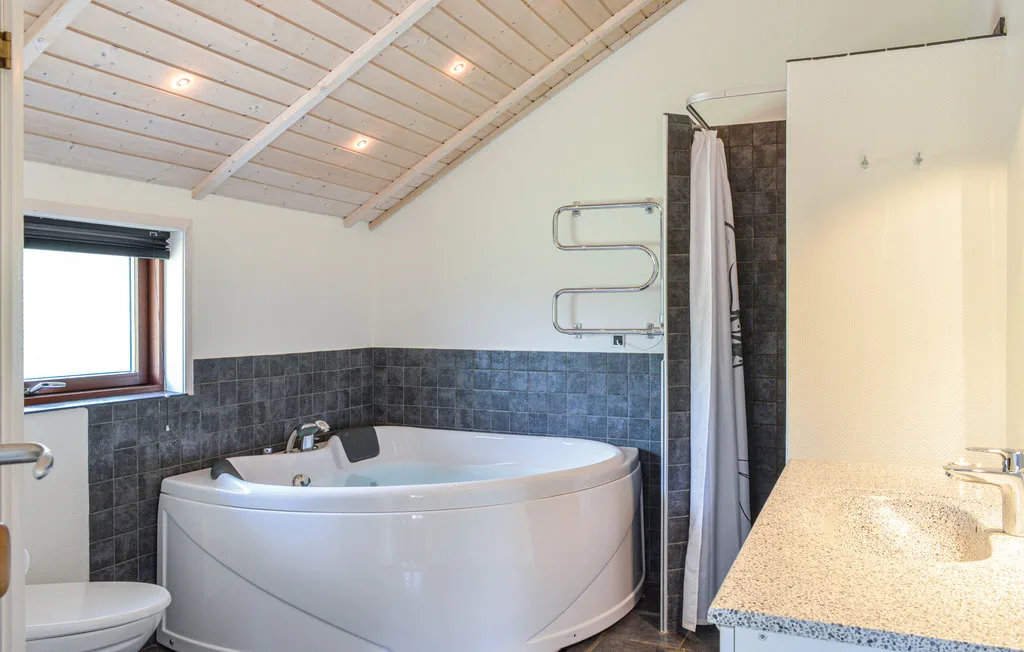 Un baño con una bañera grande, una cortina de ducha y un tocador.