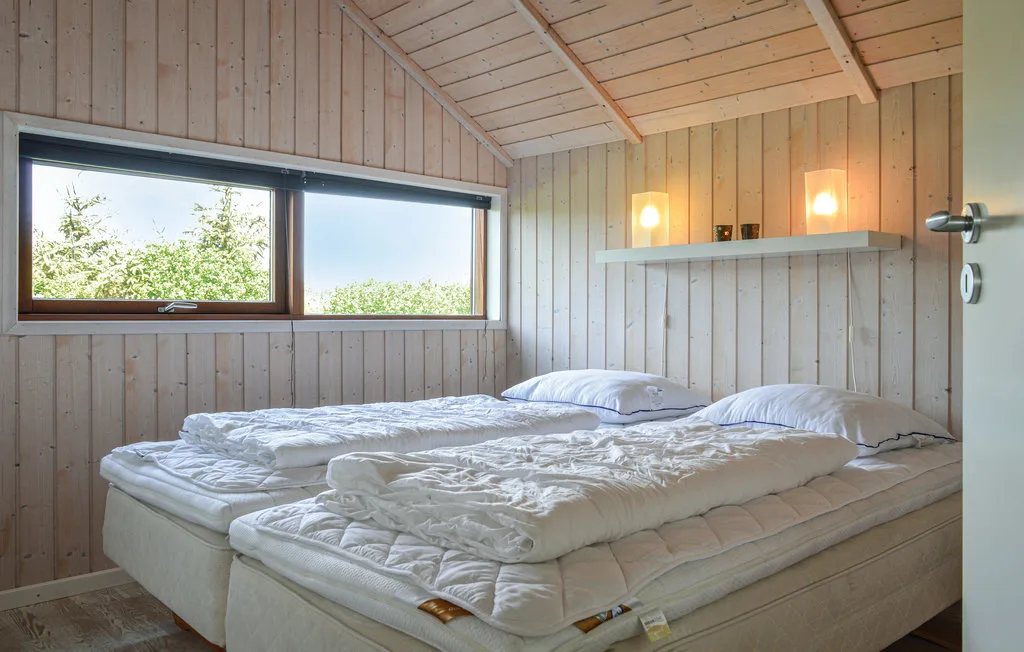 Un dormitorio con dos camas, ropa de cama blanca y una ventana amplia.