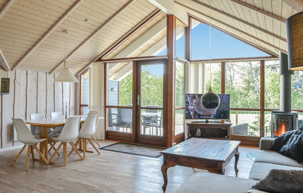 Una luminosa sala de estar y comedor con grandes ventanas y una mesa de centro de madera.