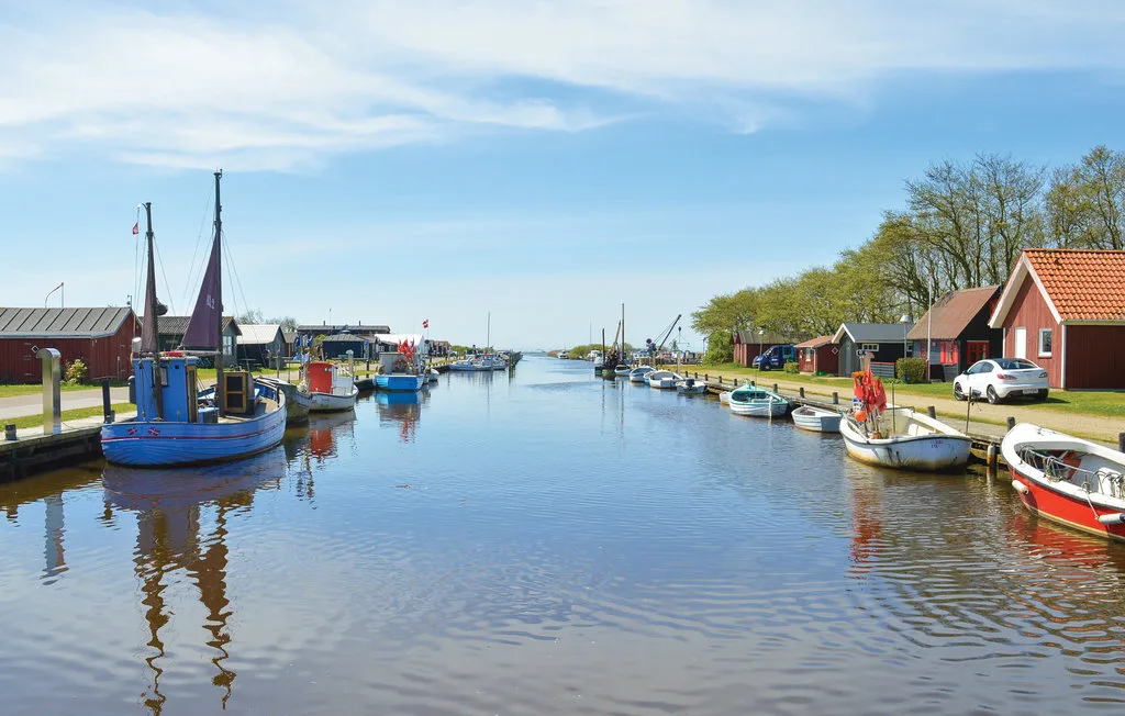 Un canal bordeado de barcos amarrados, con edificios de tejados rojos junto al agua.
