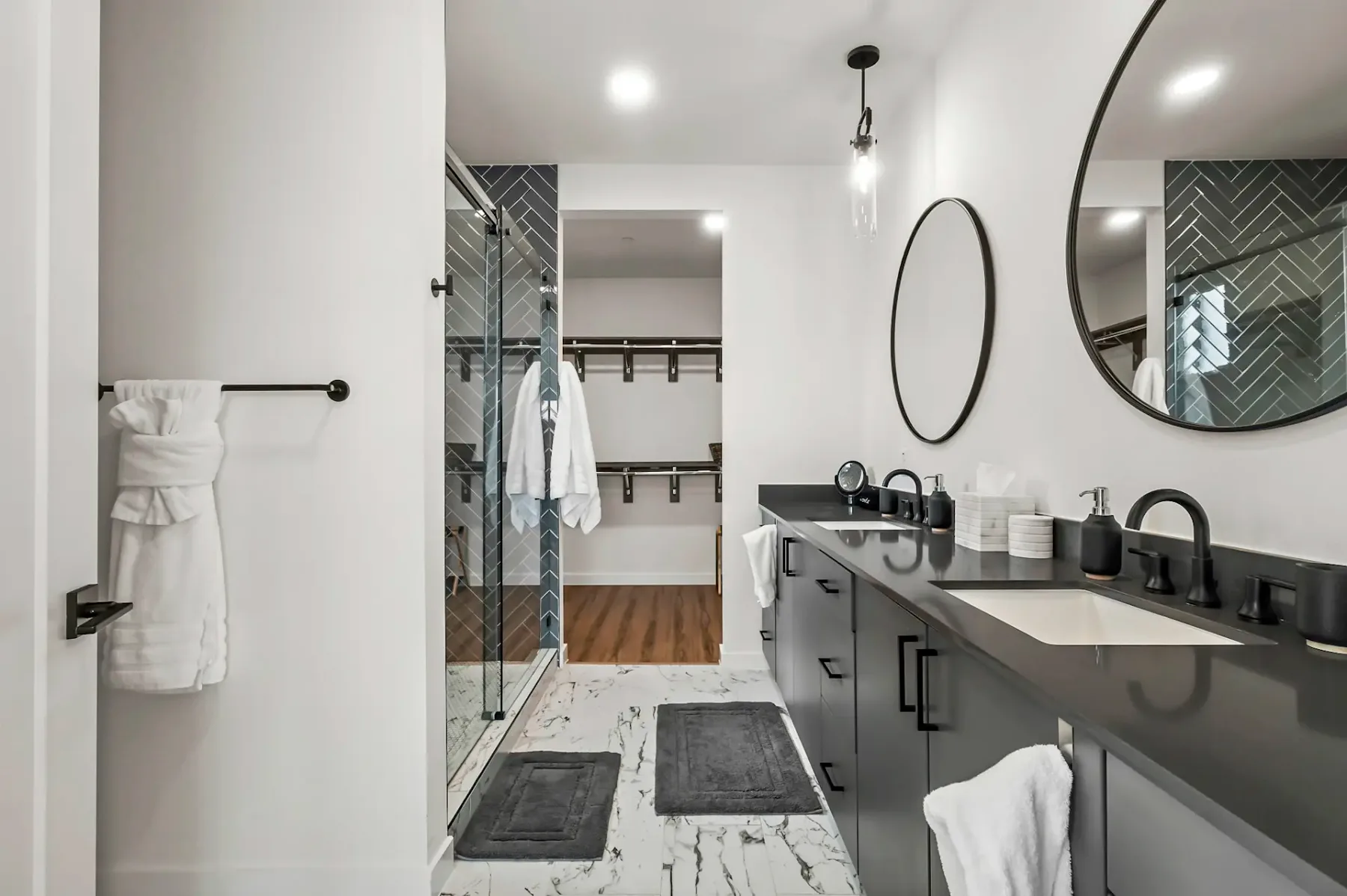 Baño con un mueble de lavabo largo y una ducha de vidrio junto a una zona de estantes abiertos.