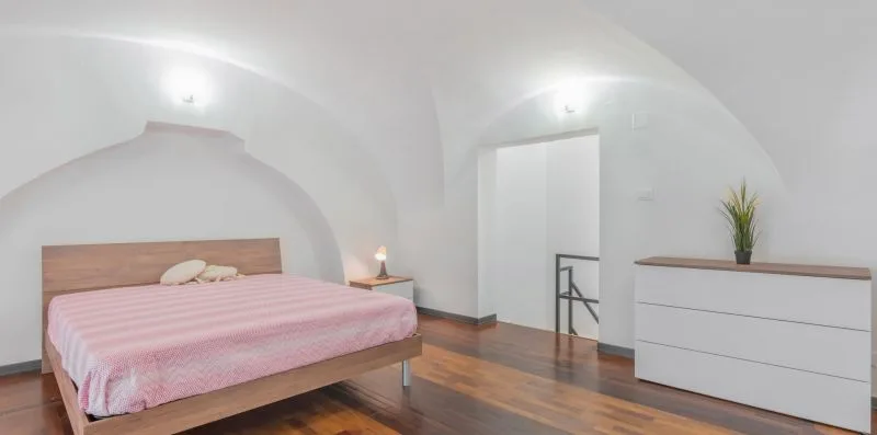 A bedroom with a pink-covered bed and a white dresser.