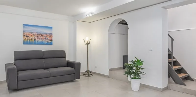 A bright living room with gray seating, a floor lamp, and a potted plant.