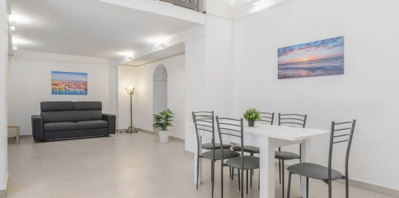 A bright living and dining area with seating, a table, and wall art.
