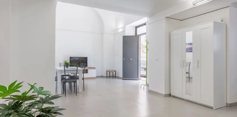 A bright room with a dining table, chairs, and a large wardrobe.
