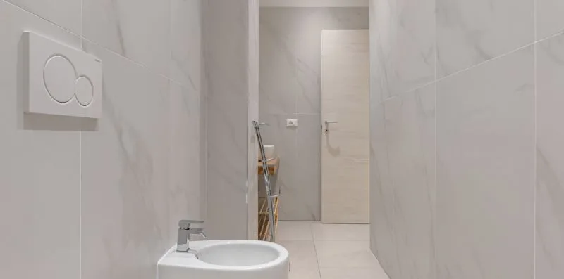 A tiled bathroom with a sink and a doorway at the far end.