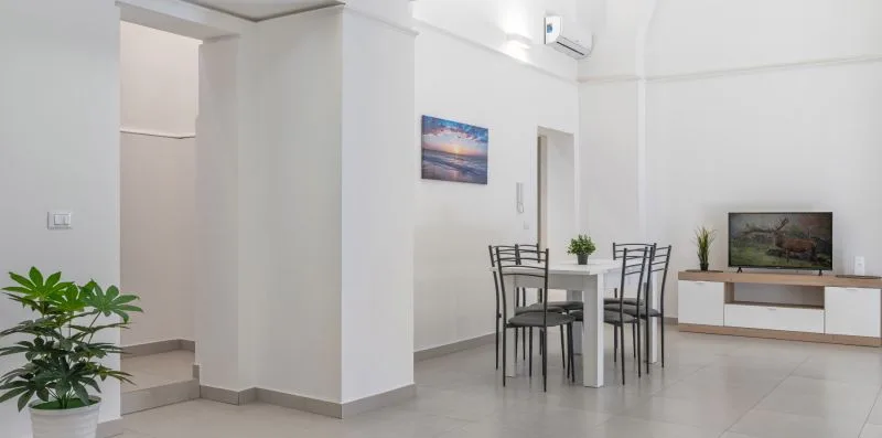 A bright living area with a dining table, chairs, and a television.