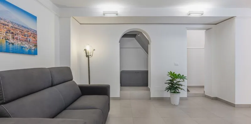 A living room with dark seating, a potted plant, and an arched doorway.