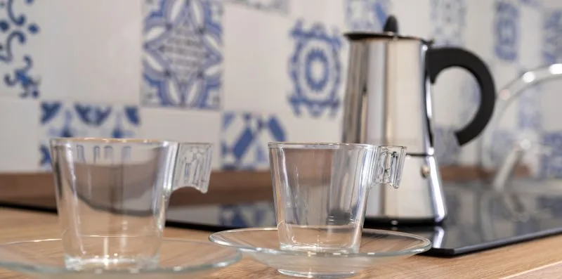 A kitchen counter displays two glass cups beside an electric kettle.
