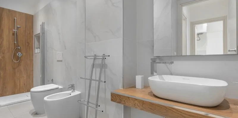 A tiled bathroom with a bathtub, toilet, bidet, and shower area.