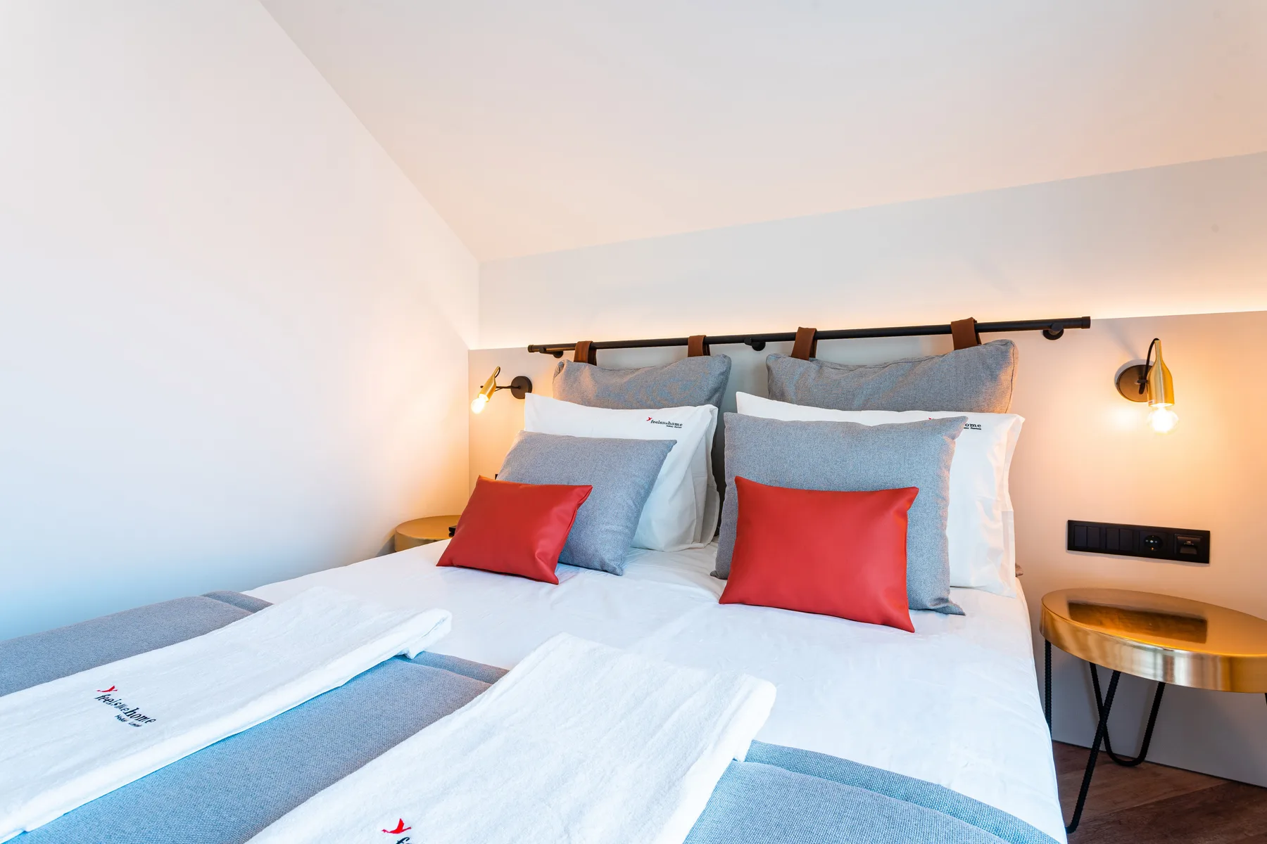 Dormitorio con una cama bien arreglada y cojines decorativos rojos.