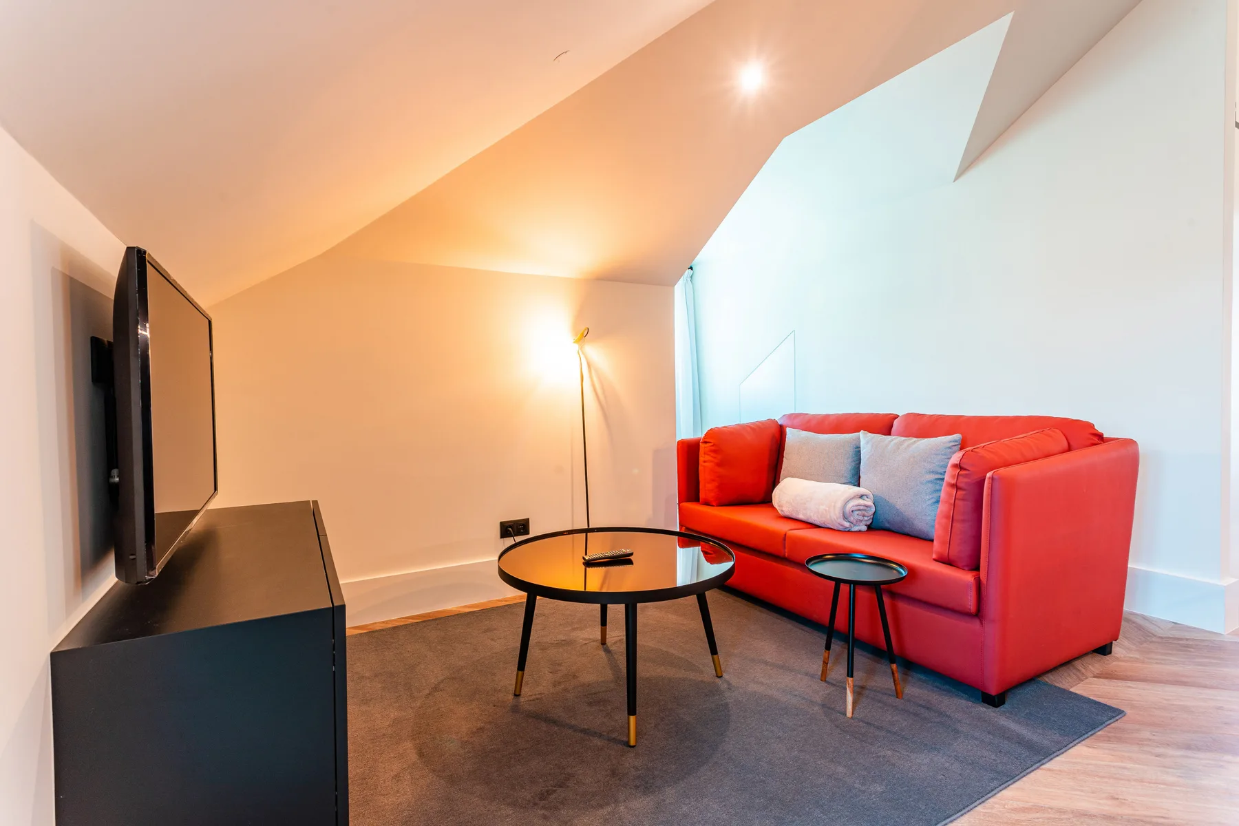 A bright living room with red seating, a coffee table, and a television.