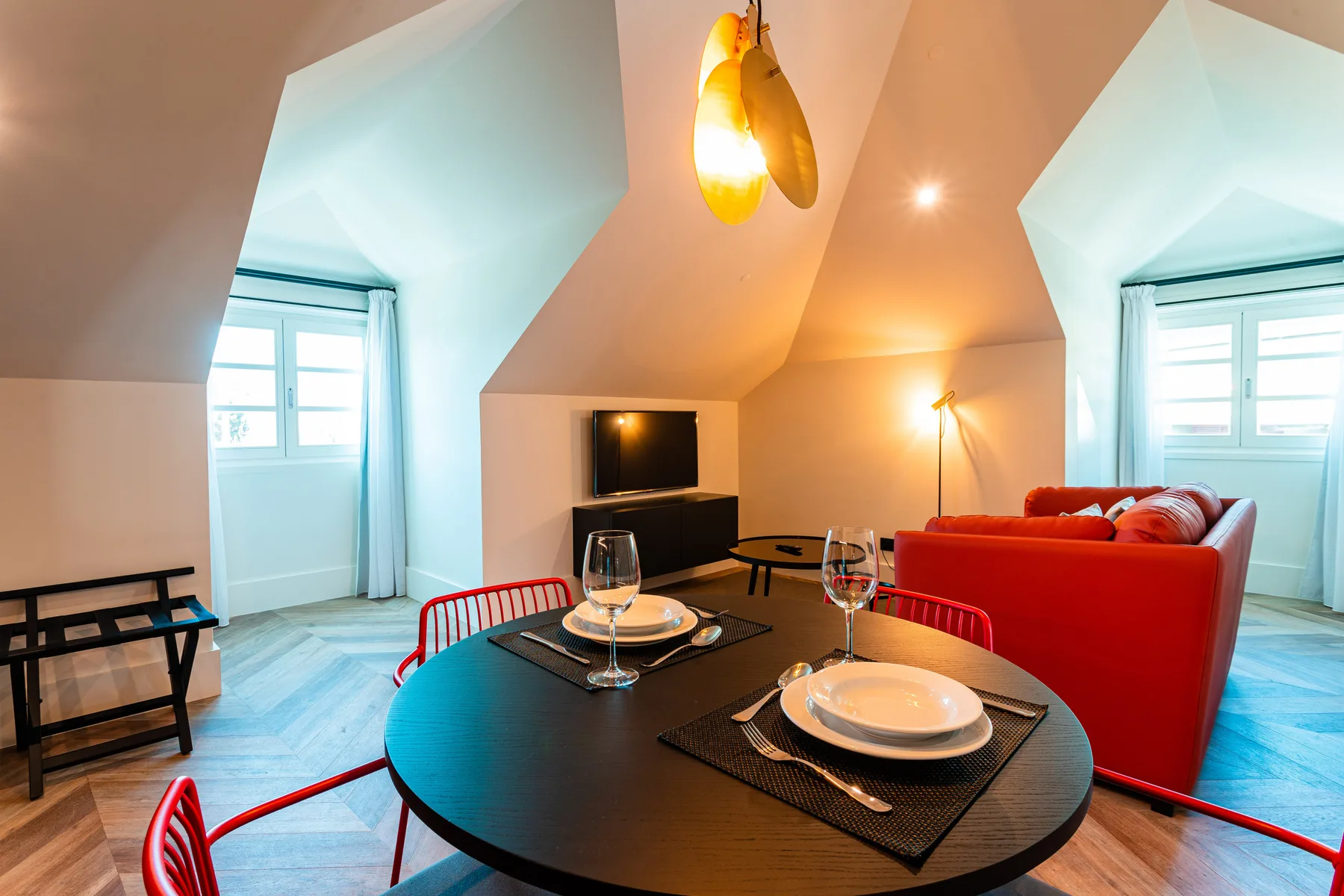 Dining area with a set table and red seating beneath a sloped ceiling.