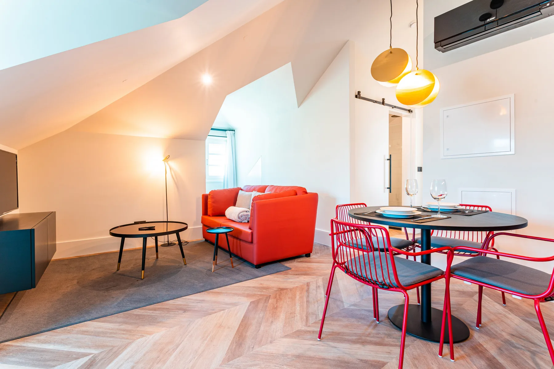 A bright living and dining area with red seating and a dining table.