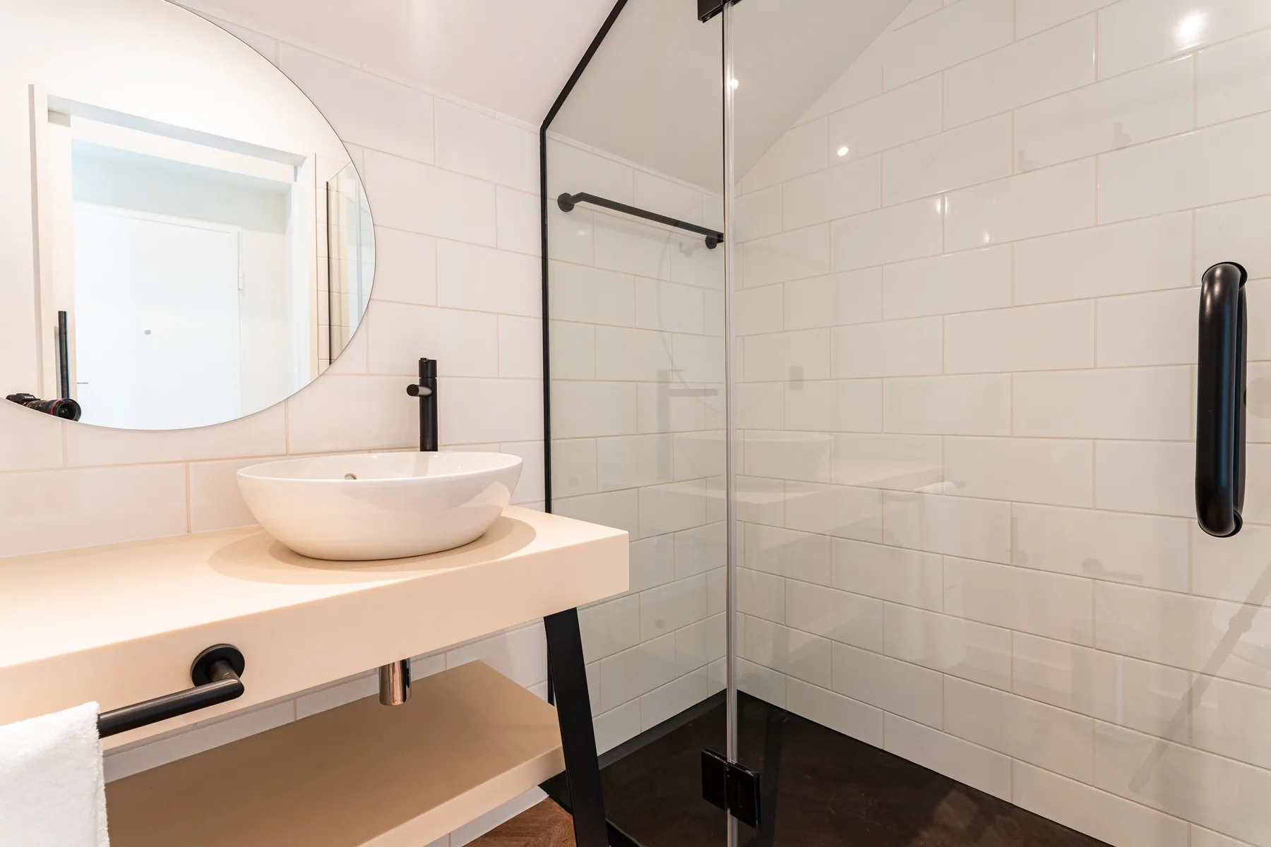 A bright bathroom with a vessel sink, mirror, and glass shower.